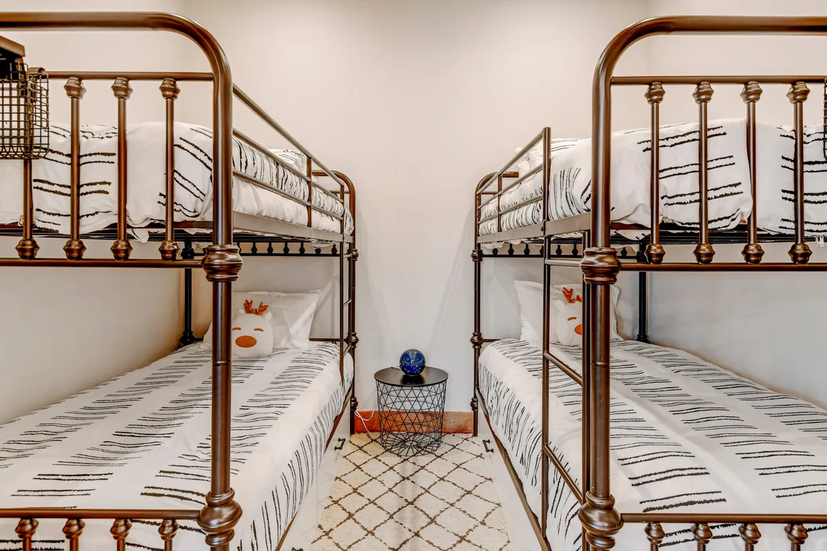 A cheerful, kid-friendly bunk room featuring bunk beds with decorative pillows and a round side table. The space feels welcoming and playful, encouraging sleepovers, reading, and creative play.