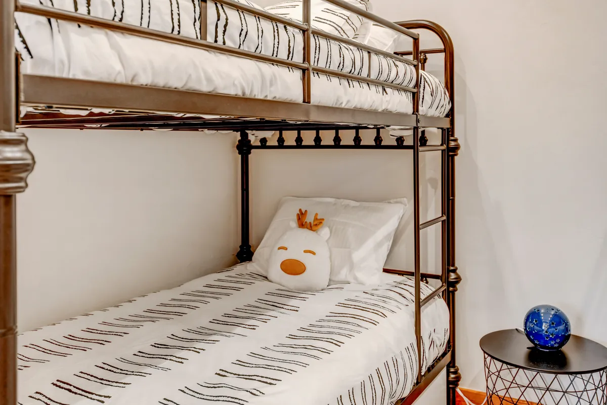 A playful bunk bed setup with a stuffed animal and nightstand, suggesting a cozy and safe environment for children. The space feels whimsical and nurturing, ideal for both play and rest.
