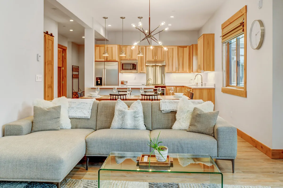 A modern, cozy living space with a sectional sofa, glass coffee table, and wood cabinetry. The room is set up for family gatherings, relaxing, or game nights, encouraging togetherness and shared activities.